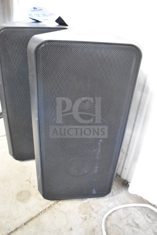 Set of 4 speakers including 2 Samsung and 2 with Onn labels, store display items. Mix of black mesh and smooth finishes.