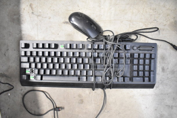 A collection of various items including a black keyboard and mouse. The keyboard has some missing keys and tangled cords.
