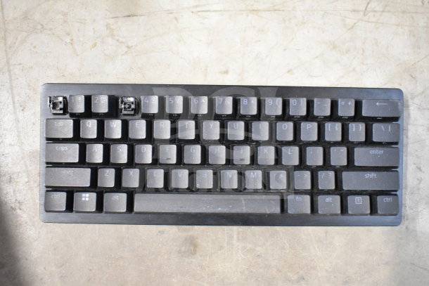 Mechanical keyboard missing two keycaps, black casing, showing switches. Visible wear, suitable for refurbishment.