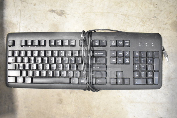 Dusty black computer keyboard with numeric keypad, wired connection, in used condition.