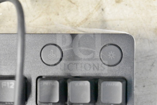 Close-up of a keyboard's top right corner showing two circular buttons with icons. Keys visible below.
