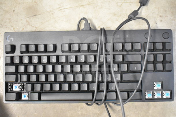 Black Logitech keyboard with missing keys and visible blue switches, slightly worn condition.