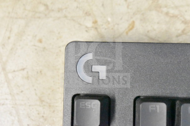 Keyboard corner with Logitech logo, featuring "ESC" and "F1" keys, part of a 20 item tech bundle including Netgear router.