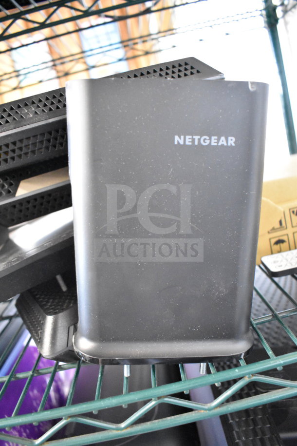 Netgear router in black, visible logo, slight wear. Part of auction lot including keyboards and computer mice.