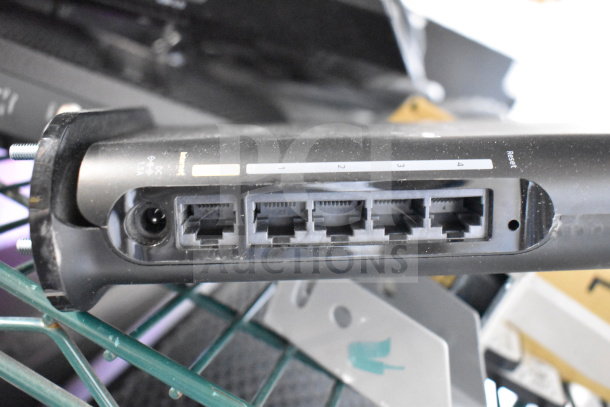 Netgear router with four Ethernet ports, visible power input, and reset button, included in a lot of 20 technology items.