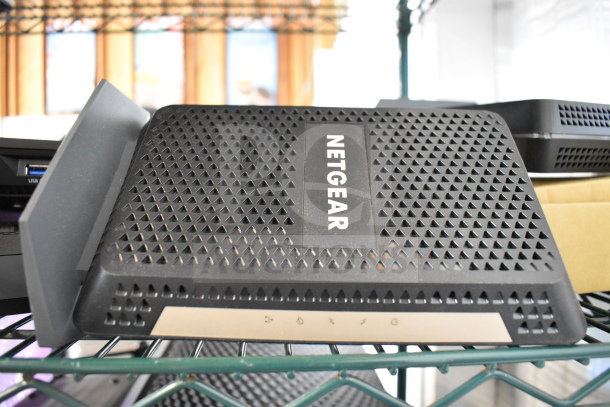 Netgear router with perforated design on a shelf. Labels show USB port and indicator symbols. Part of a 20-item auction.