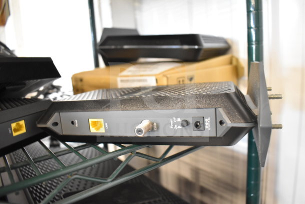 Netgear router with LAN, cable, and power interfaces on a shelf. Part of a 20-item auction lot.