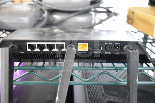 Netgear router with five Ethernet ports, USB 2.0, power switch, and antennas, on a metal shelf.