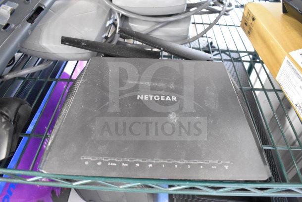 Netgear router with visible logo, slight wear on surface; part of a lot including keyboards and mice.