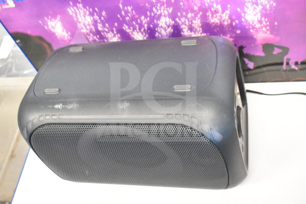 Onn Medium Party Speaker, black with visible wear, on display. Features built-in handle, mesh grille, and wired connection.