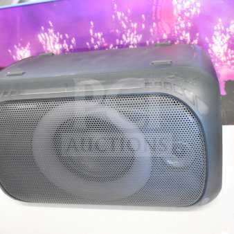 Onn medium party speaker display. Black casing, mesh front, vibrant backdrop. Condition: used, some wear visible.