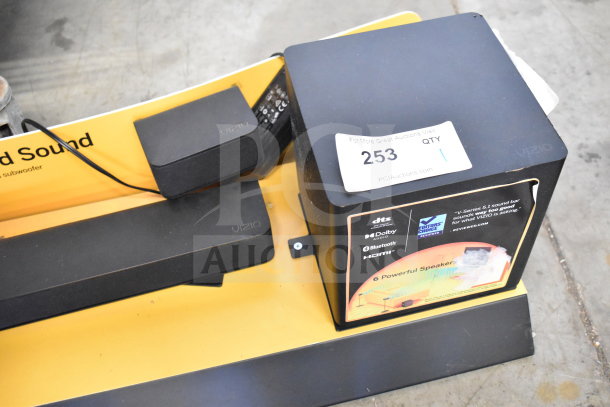 Vizio sound bar and speaker on store display, featuring Dolby Audio, Bluetooth, and HDMI. Auction tag reads "253 QTY 1."