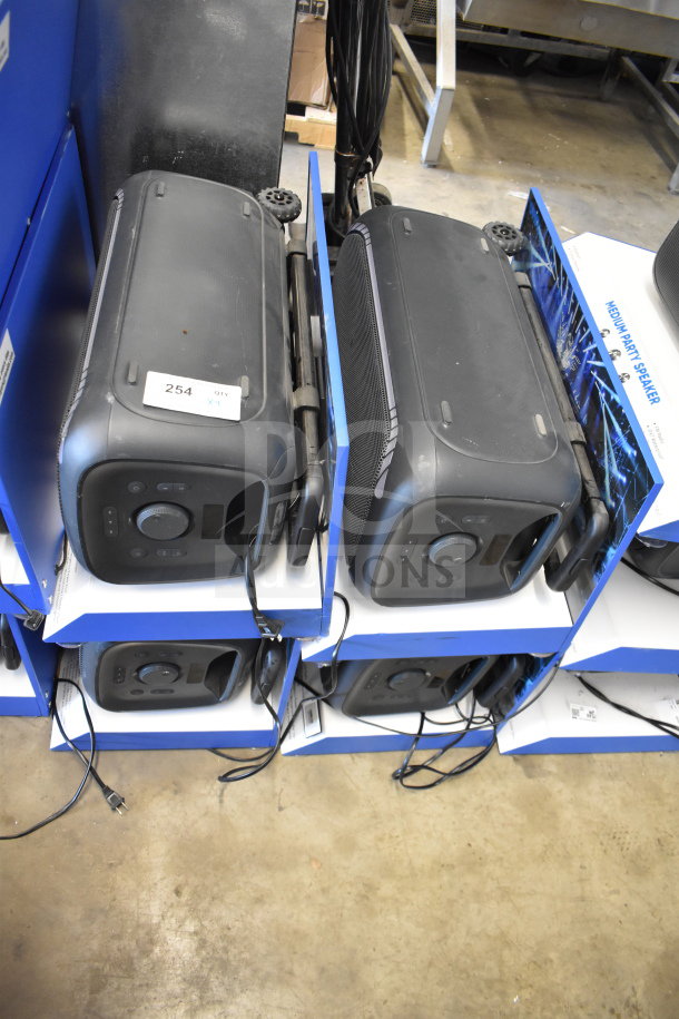 Four Onn large party speakers displayed in-store, with control panels visible and power cords attached. Quantity label reads "254, QTY X4."
