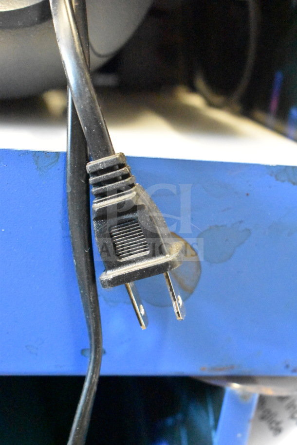 Power cord of Onn Large Party Speaker. Plug detail shown against a blue store display surface. Perfect condition.
