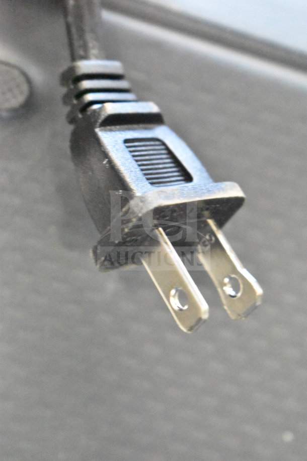 Close-up of a two-prong power plug, details of the Onn Large Party Speaker not visible.