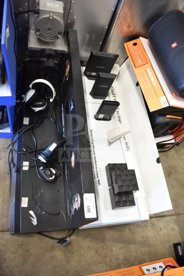 Store display with Netgear routers and headphones in used condition. Includes box labels and product tags.