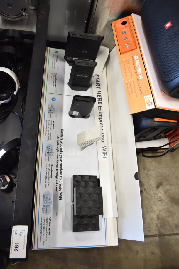 Store display featuring Netgear routers and JBL headphones, various models. Includes display board with specifications.