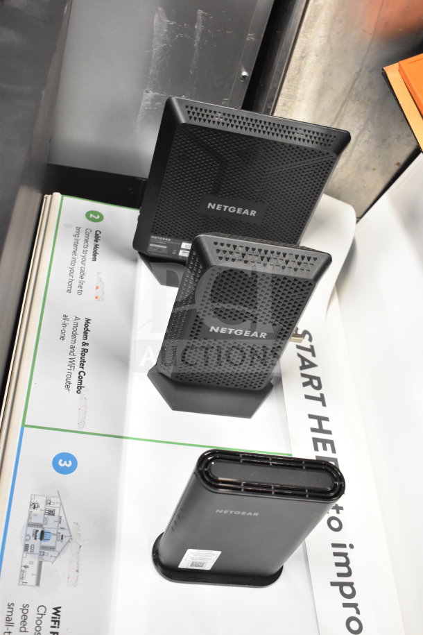 Netgear routers on store display, featuring sleek black design. Includes modem and WiFi router combo. Ideal for high-speed internet.