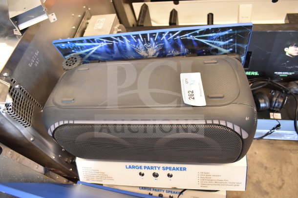 Store display with Onn Large Party Speaker featuring Bluetooth, 12-hour playback, and multicolor LED lights. Auction tag visible.