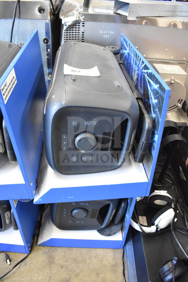 Onn large party speaker on a blue store display. Features control panel and handle. Used condition, tag indicates auction lot 262.