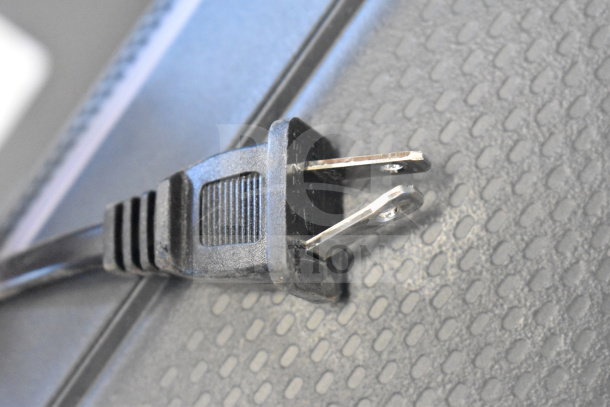 Power plug of Onn Large Party Speaker on textured surface, used for store display.