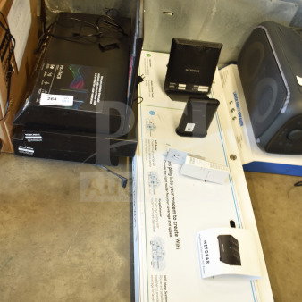 Store display with multiple items including Netgear routers and accessories. Box label indicates networking equipment.