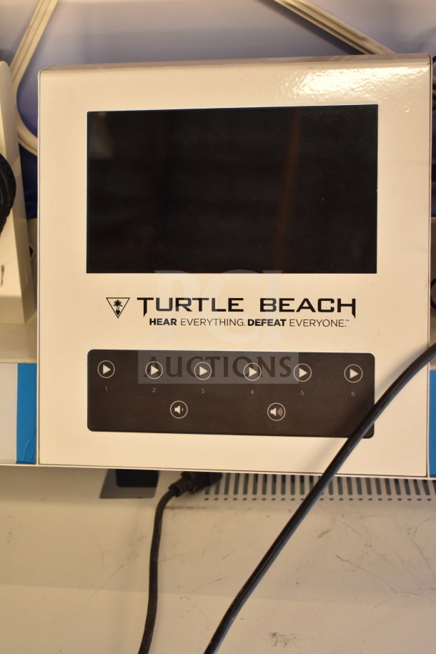 Turtle Beach store display with monitor and headphones. Features multiple control buttons; brand logo and slogan visible. Appears in used condition.