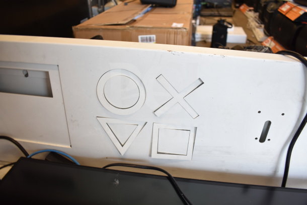 Store display with iconic PlayStation symbols, featuring a monitor and headphone setup. Minor wear, ideal for gaming enthusiasts.