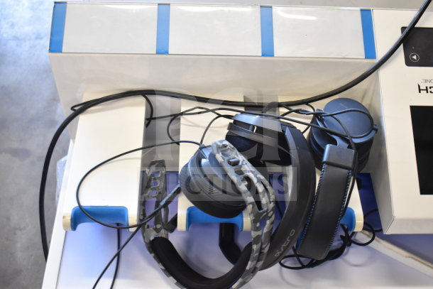 Store display featuring multiple Astro headphones and a monitor, set on a counter with blue accents. Cables are visible.