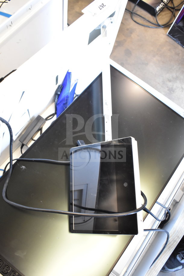 Store display with black monitor and tangled cables. Includes headphones. Visible label reads "267." Stored on a counter.