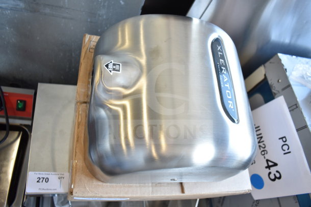 Brand new XLERATOR XL-SB hand dryer, stainless steel cover, 110/120V, with minor scratches, label indicating "Feel the Power".