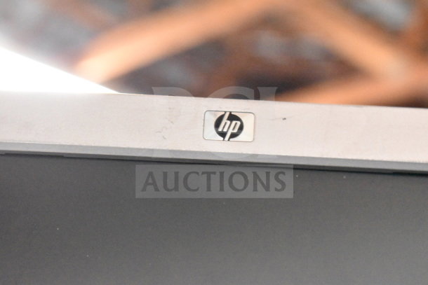 HP monitor close-up showing the logo, part of a lot of four including Dell, in used condition with visible wear.