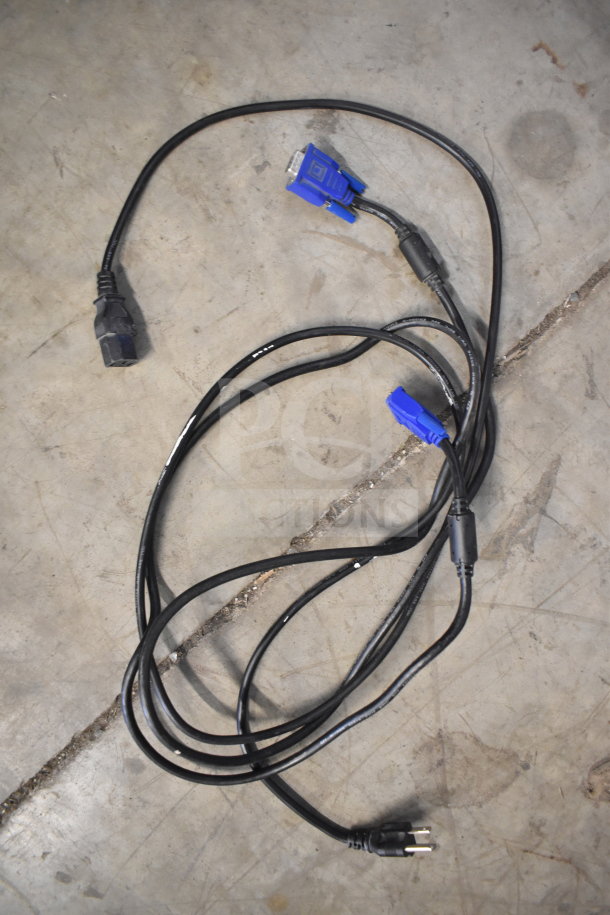 Coiled black VGA and power cables on a concrete floor, suitable for connecting monitors.