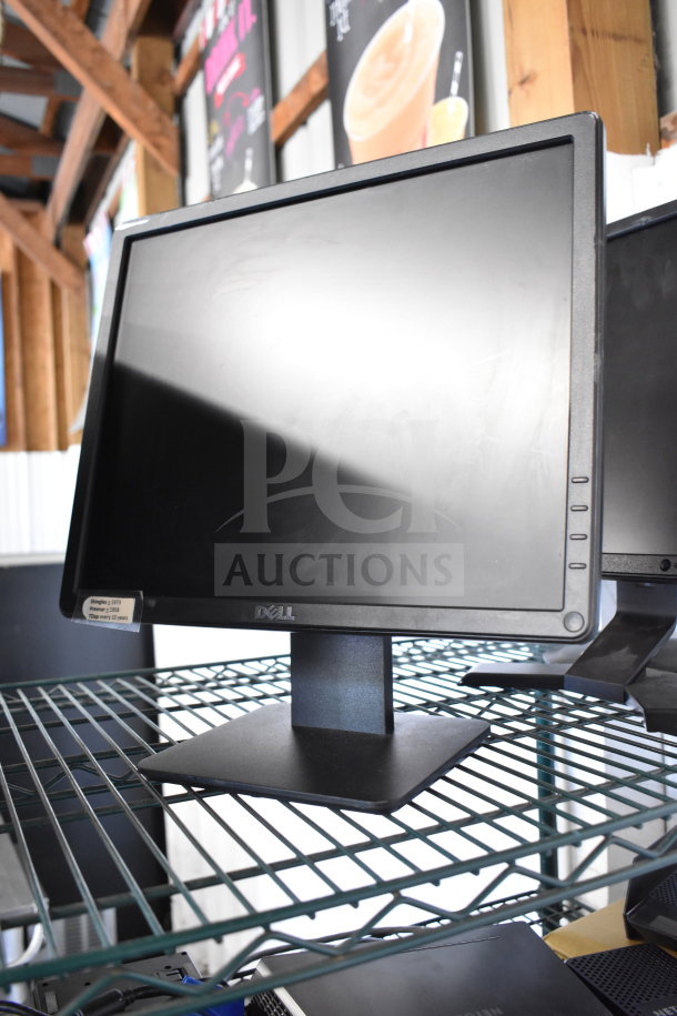 Four various monitors including Dell and HP models on a metal shelf, in good condition, with visible label on Dell monitor.