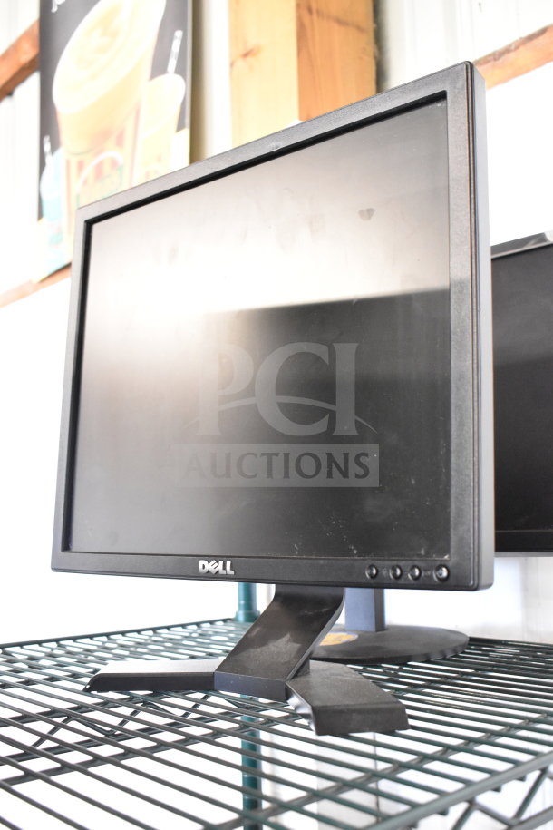 Four monitors including Dell and HP, displayed on a wire rack. Monitors show slight wear. Auction offers 4 for 1 bid.
