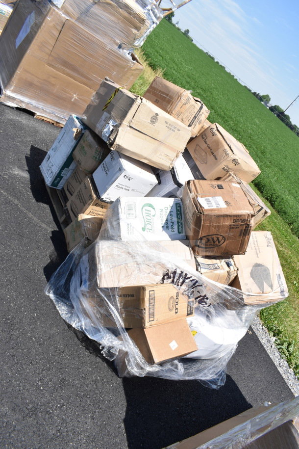 Boxes of new scratch and dent items including cold cups, sporks, forks, plates; various brands, outdoor setting.