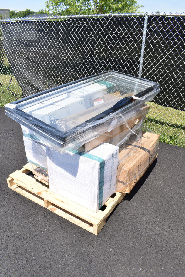 Sealed pallet with 17 scratch and dent items, including glass door and grill brush, on wooden pallet outdoors.