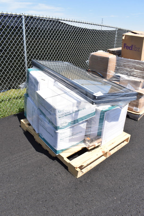 Pallet with brand new scratch and dent items, including a glass door and grill cleaning brush, sealed in packaging.