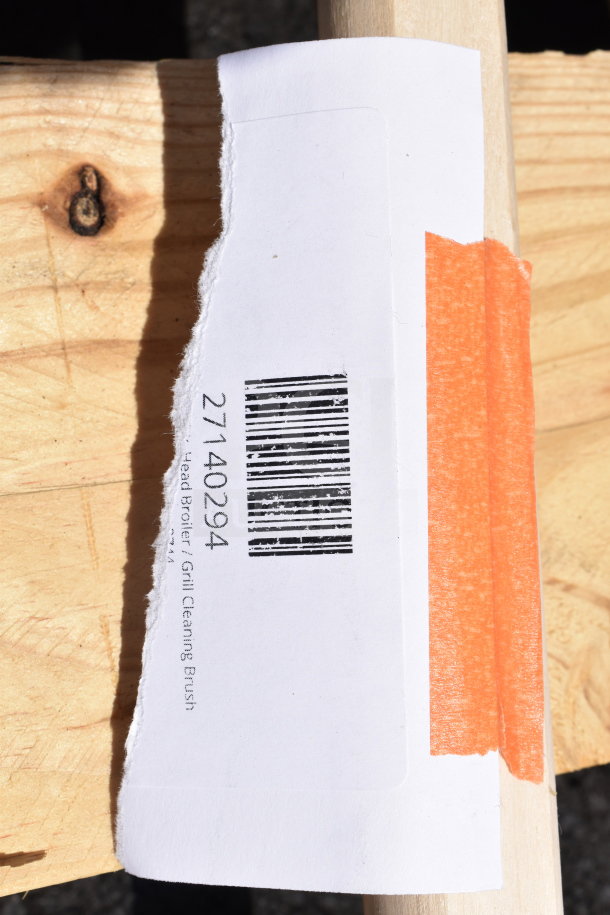 Label with barcode and "Grill Cleaning Brush" text on wooden surface; auction scratch and dent item.