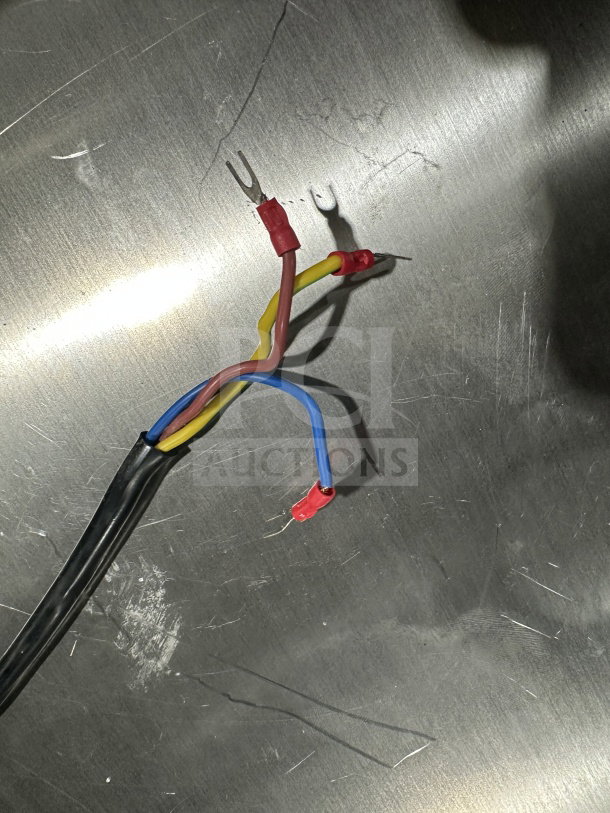 Close-up of colorful electrical wires with red connectors on a stainless steel surface. No visible labels or tags.