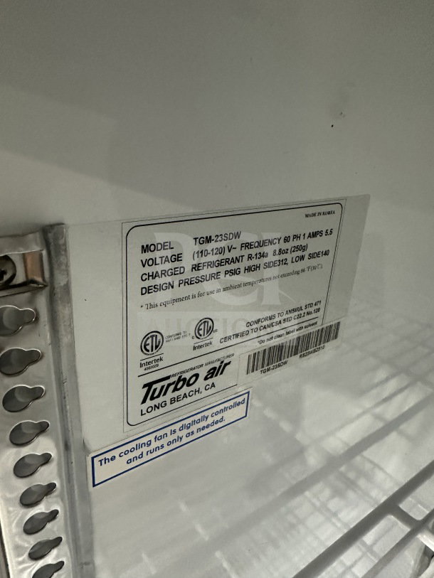 Turbo Air TGM23SDW commercial fridge label showing model, voltage, refrigerant, and safety certifications, with poly-coated rack.