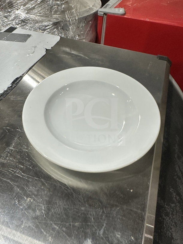 White ceramic dinner plate on a metal surface, good condition, simple design, ideal for everyday use or collection.
