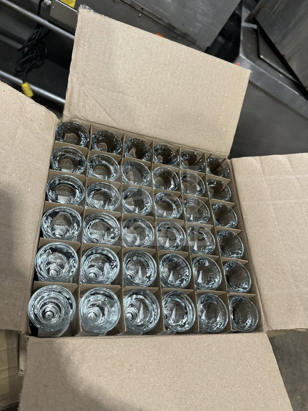 Box of 72 brand new Anchor Hocking 1 oz clear glass whiskey shot glasses, Model 3668U, neatly arranged.