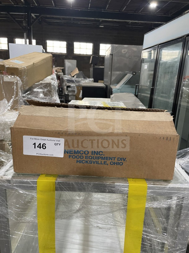 Cardboard box labeled "Nemco Inc. Food Equipment Div." on pallet, wrapped in plastic, inside warehouse with equipment.