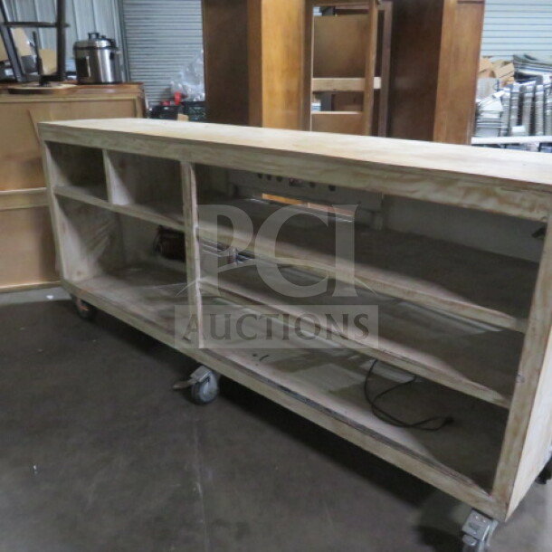 Wooden portable bar on heavy-duty casters; features six under-storage shelves. Dimensions: 99x24x43 inches.