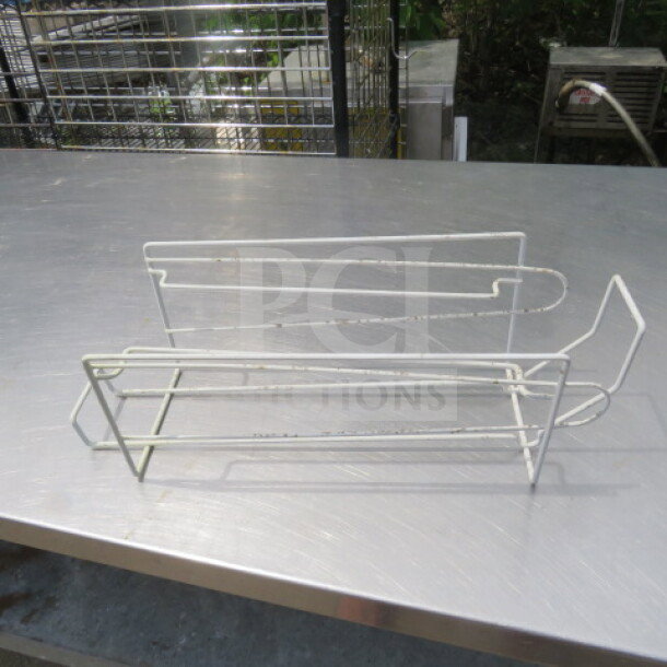 White wire can holder with a minimalist design. Holds one can, slightly worn with some rust spots. Suitable for kitchen storage.