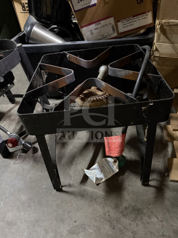 Black metal propane burner with sturdy frame and one burner. Visible labels for safety instructions. Used condition.