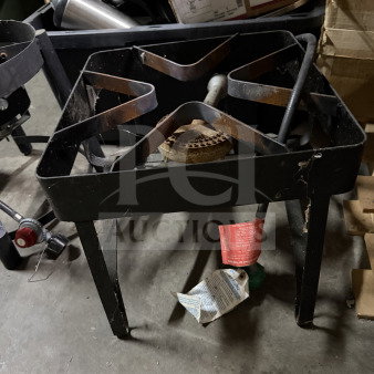 Black metal propane burner with sturdy frame and one burner. Visible labels for safety instructions. Used condition.