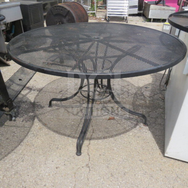Black metal round patio table with umbrella hole, 48x29 inches, mesh top, sturdy curved legs, suitable for outdoor use.