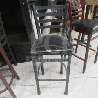 Bar height black metal chair with ladder back design, cushioned seat showing wear. Ideal for bars or home use.